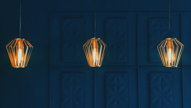 Modern chandelier design with warm light bulbs hanging against a dark blue textured wall