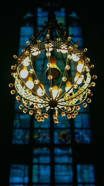 Golden chandelier with glowing lights and crystal decorations in dark room   Copy