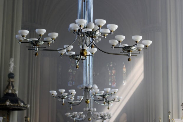 Modern chandelier design with multiple arms and white lampshades in a large hall