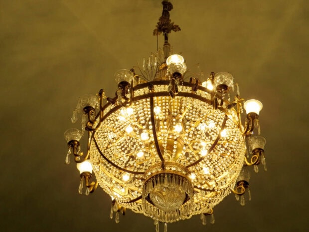 Ornate chandelier with crystal beads and lit bulbs hanging from ceiling   Copy