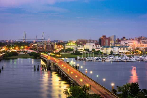 Evening view of Charleston South Carolina cityscape with bridge and marina lights reflecting on water
