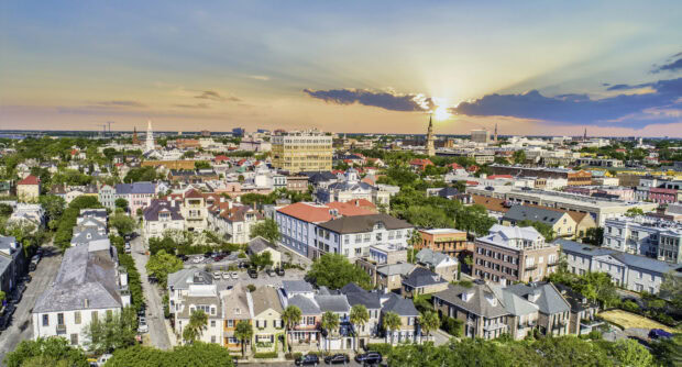 A vibrant cityscape of Charleston South Carolina during sunset with historic buildings and lush greenery