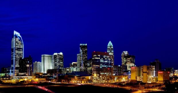 The Charlotte North Carolina skyline shines brightly against the night sky in this vibrant city view, 2K Desktop Wallpaper