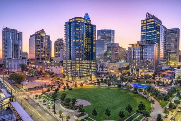 The Charlotte North Carolina skyline glows warmly as the sun sets over the city, 2K Desktop Wallpaper