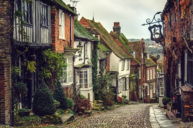 A cobblestone street lined with historic houses and lush greenery in the United Kingdom, HD Desktop Wallpaper