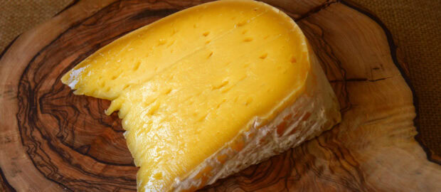 A close up of cheese on a wooden cutting board with detailed texture