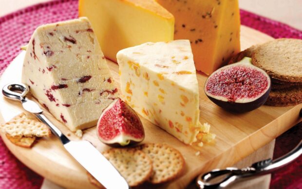 A variety of cheese with figs and crackers on a wooden board for cheese display