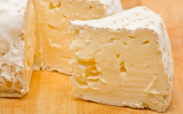 A close up of soft cheese with a creamy texture on a wooden surface