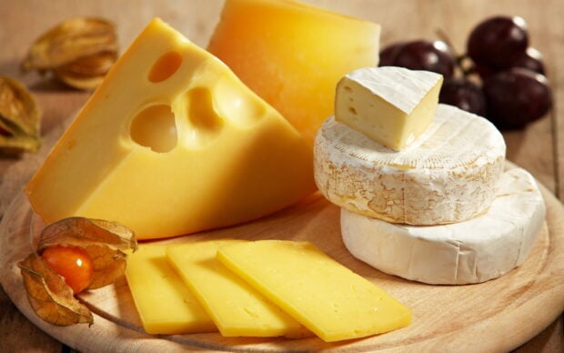A variety of cheese on a wooden board showcasing different types of cheese