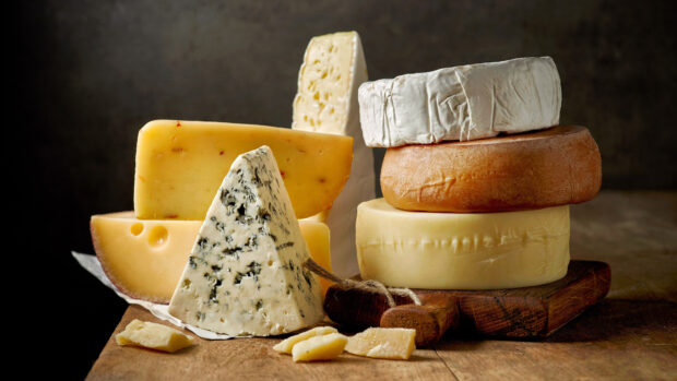 Various cheese types arranged on a wooden board featuring cheese