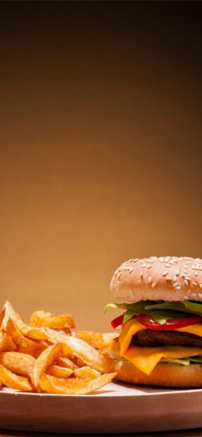 A cheeseburger with melted cheddar and fresh veggies served with crispy French fries on a wooden plate, 2K Phone Wallpaper