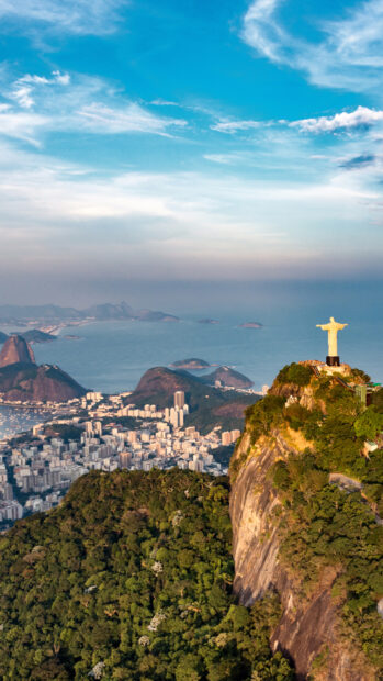The Christ The Redeemer statue stands tall above Rio de Janeiro with the city and ocean in the background, 4K Phone Wallpaper