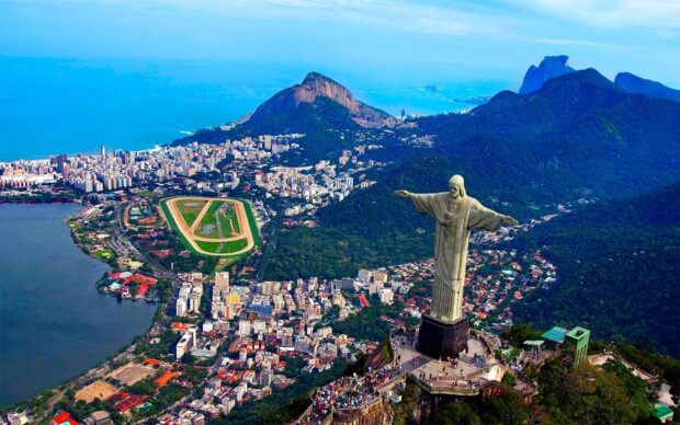 The Christ The Redeemer statue stands tall above the city of Rio de Janeiro with mountains and ocean in the background, 2K Desktop Wallpaper