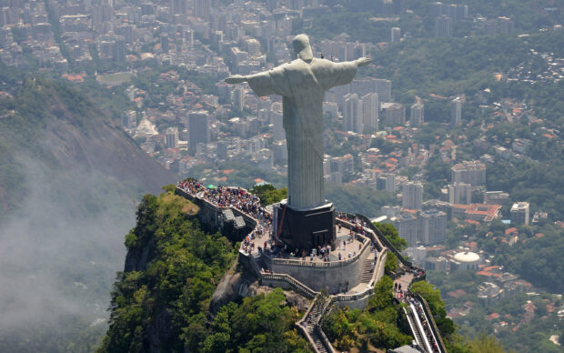 The Christ The Redeemer statue stands tall above the city with visitors around its base, 2K Desktop Wallpaper