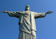 Statue of Christ the Redeemer in Rio de Janeiro, Brazil, with outstretched arms on a clear blue sky.