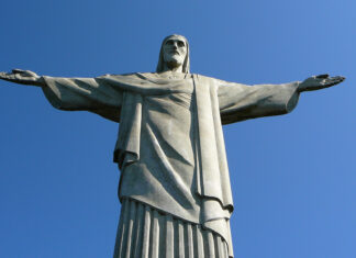 Statue of Christ the Redeemer in Rio de Janeiro, Brazil, with outstretched arms on a clear blue sky.