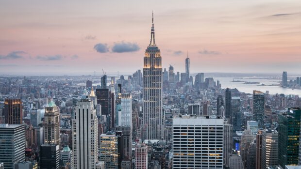 Tall city skyline with skyscrapers including a prominent building at sunset