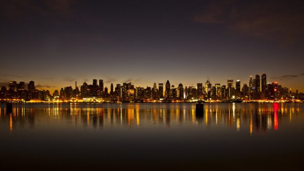 City skylines at dusk with illuminated buildings reflecting on the water