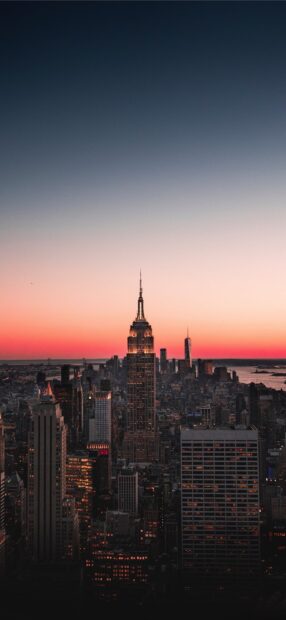 A stunning city skylines view at sunset with illuminated buildings and a colorful sky