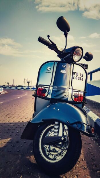 A blue Bajaj scooter is parked on a sunny road under a clear sky, HD Mobile Wallpaper