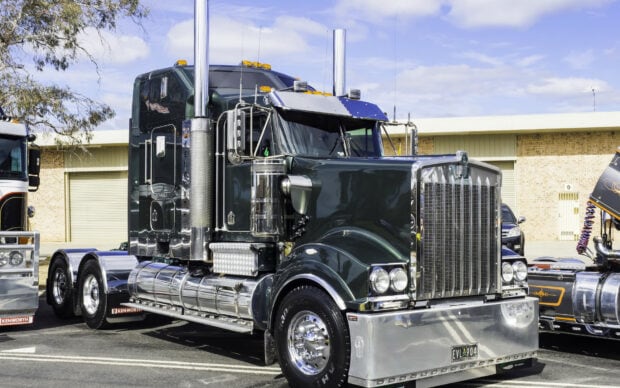 A Kenworth truck is parked in an industrial area under a clear sky, HD Desktop Wallpaper