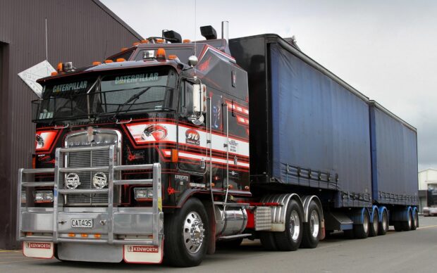 A black and red Kenworth truck with a large blue trailer parked at a loading area, HD Desktop Wallpaper