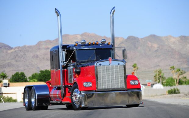 A classic Kenworth truck with red and black colors is parked on a desert road with mountains in the background, HD Desktop Wallpaper