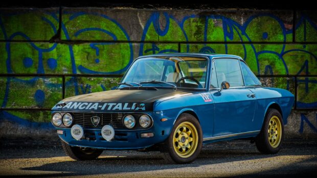 A vintage blue Lancia car with yellow wheels parked in front of a colorful graffiti wall, HD Desktop Wallpaper