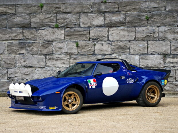 A classic blue Lancia car is parked in front of a stone wall, HD Desktop Wallpaper