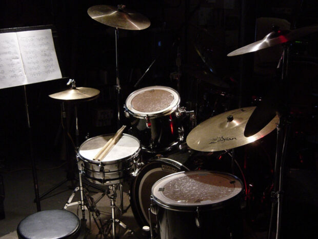 A classic drum set with cymbals and sticks is displayed in a dimly lit room, HD Desktop Wallpaper