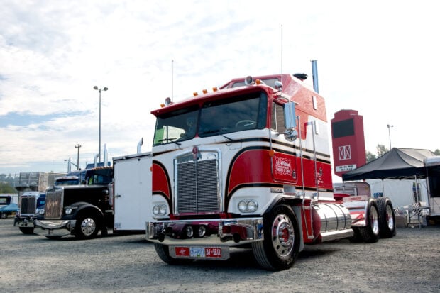 A classic red Kenworth truck parked outdoors during a truck show event, HD Desktop Wallpaper
