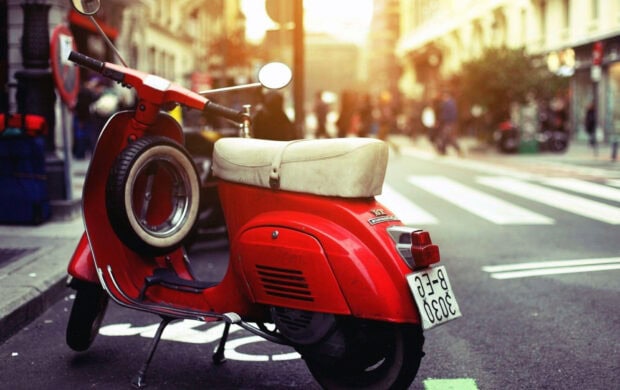 A red scooter with a white seat parked near a crosswalk on a busy urban street, HD Desktop Wallpaper