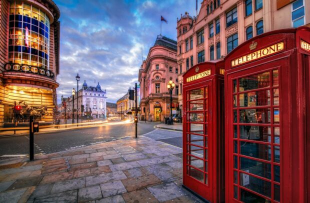 Two iconic red telephone booths stand on a city street with historic buildings in the United Kingdom, HD Desktop Wallpaper