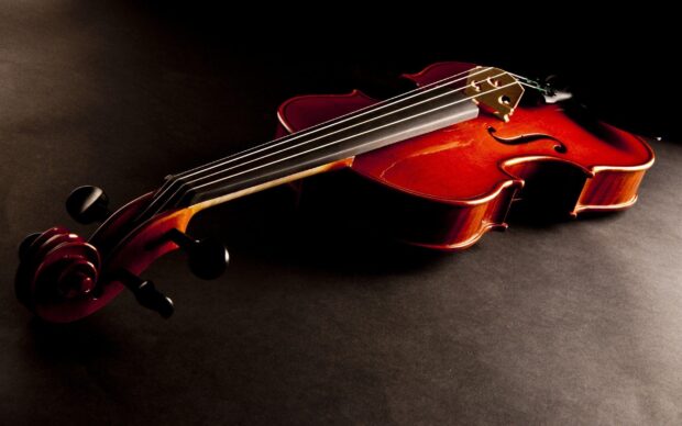 A classic violin is placed on a dark surface showing its strings and scroll, 2K Desktop Wallpaper