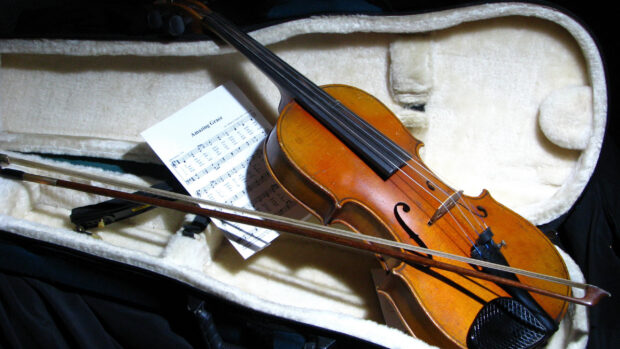 A classic wooden violin rests in a soft case with its bow and sheet music inside, 2K Desktop Wallpaper