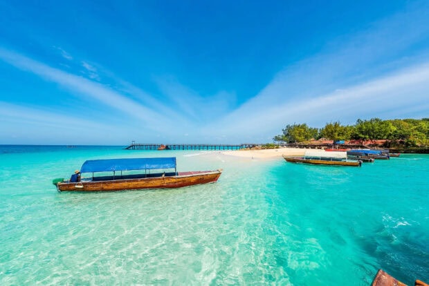 A bright day in Zanzibar with clear waters and wooden boats near the shore, HD Desktop Wallpaper