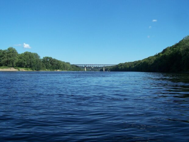 A clear blue sky and flowing water on the Mississippi River with a bridge and green trees, 2K Desktop Wallpaper