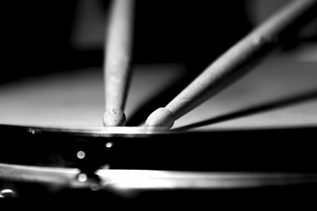 A close up of drumsticks striking the drum surface in black and white, 2K Desktop Wallpaper