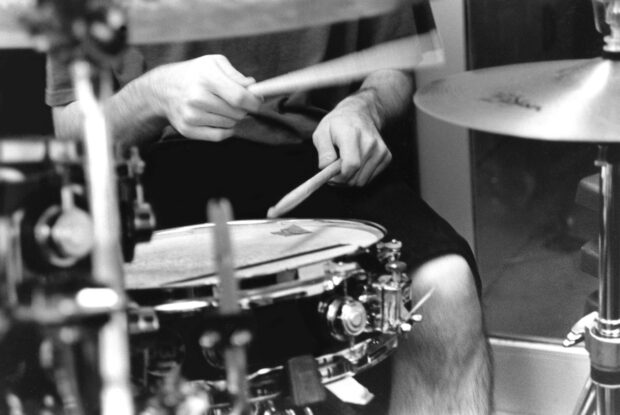 A drummer is playing drums with drumsticks in a black and white setting, HD Desktop Wallpaper