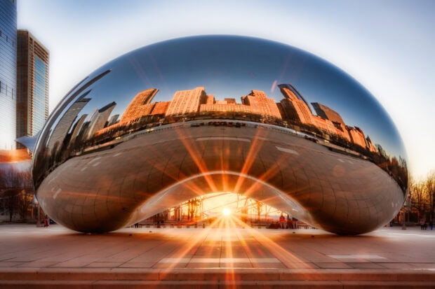The Cloud Gate sculpture reflects the Chicago skyline during sunset with sun rays shining through, 2K Desktop Wallpaper