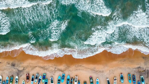 Aerial shot of waves crashing near boats on Sri Lanka shore, 4K Desktop Wallpaper