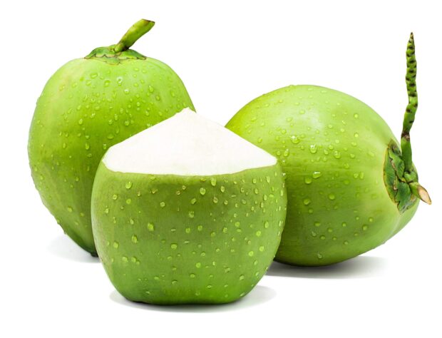Fresh green coconuts with water droplets and one cut open to show white flesh