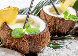 Fresh coconut drink with pineapple slices and mint leaves on white stones