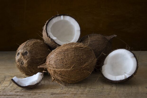 Fresh coconut shells with white flesh on a wooden surface in natural light