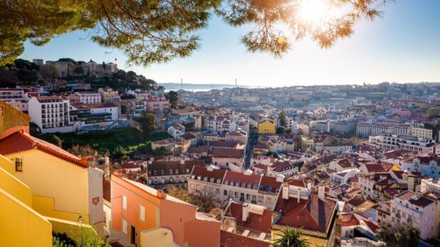 A scenic view of Lisbon Portugal featuring colorful buildings and a historic castle under the sun, 2K Desktop Wallpaper