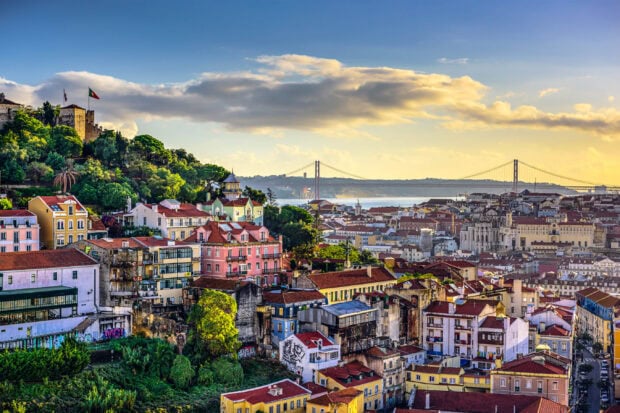 A scenic view of Lisbon Portugal with old buildings and the 25 de Abril Bridge in the background, 2K Desktop Wallpaper