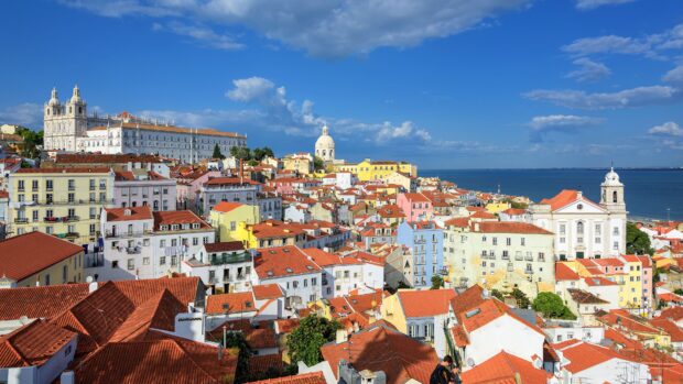 The Lisbon Portugal cityscape shows vibrant houses against the ocean, 4K Desktop Wallpaper