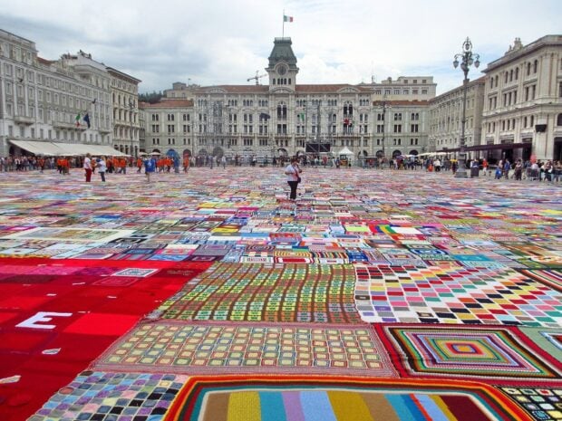 A vibrant crowd explores a colorful patchwork display in Trieste city square, HD Desktop Wallpaper