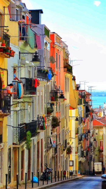 A vibrant street scene shows colorful buildings and balconies in Lisbon Portugal, HD Mobile Wallpaper