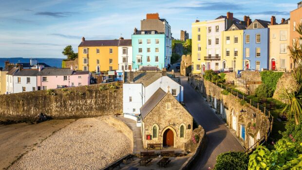 A stone chapel and pastel colored buildings line a quiet street near the beach in Wales, HD Desktop Wallpaper